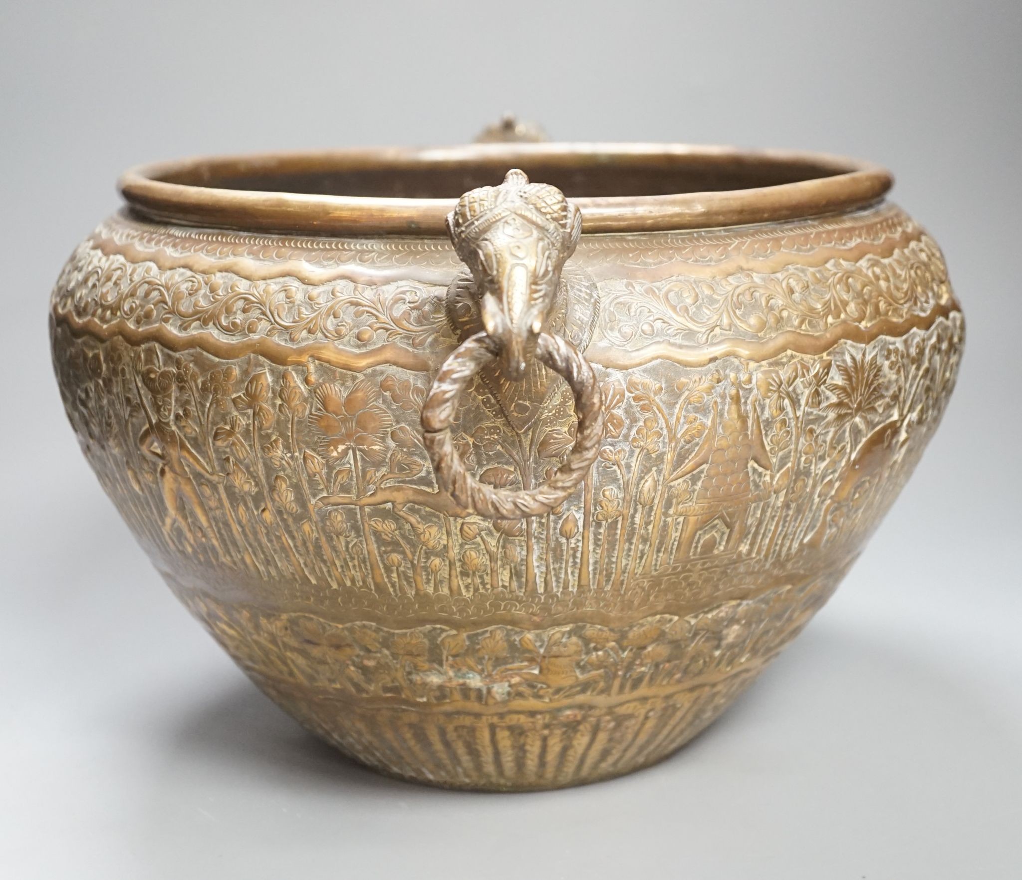 19th century hand engraved British Indian brass jardinière planter vase, finely engraved depicting scenes in an Indian forest with game hunting and elephants; with elephant head handles; original patina.